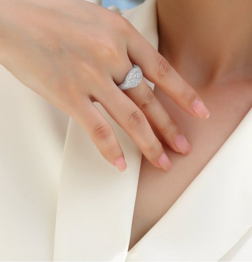 Close-up of a hand wearing a moissanite ring on a white background